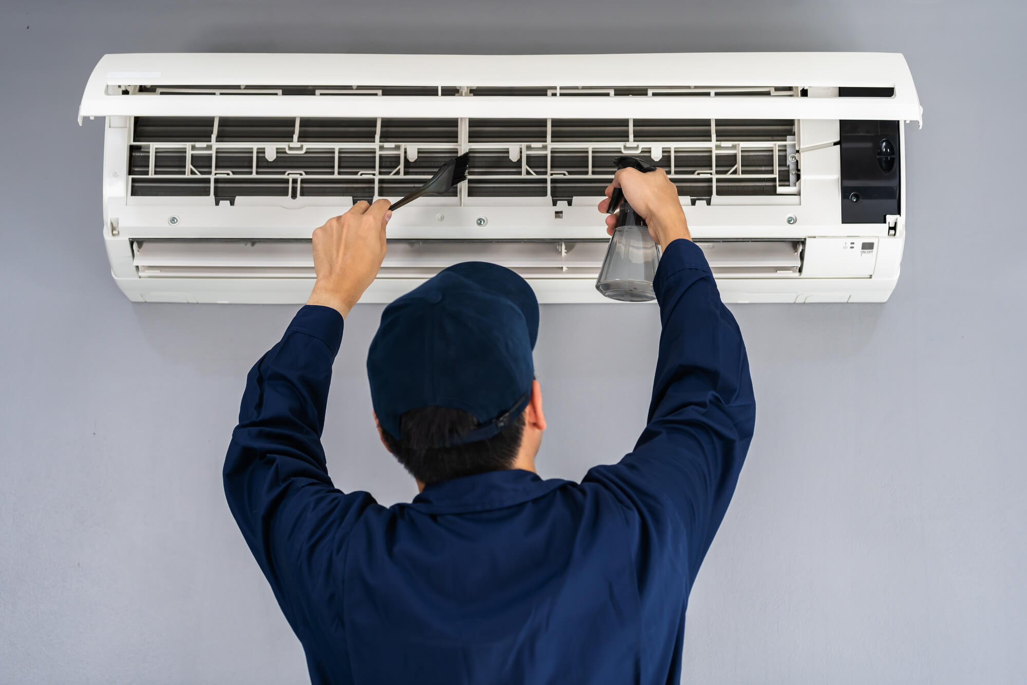 a worker cleaning a dirty MINI SPLIT AC